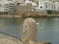 La playa del port vell, a la derecha, en el mar, la roca del Cargoll y al fondo Ampurias